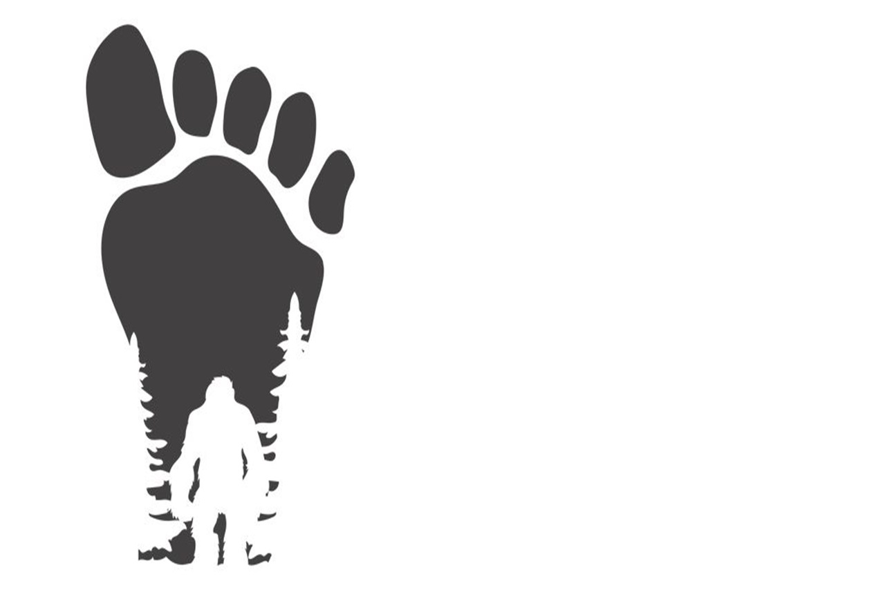 A dark outline of a foot with the silhouette of Bigfoot standing in the heal of the foot.